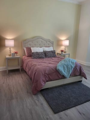 A cozy bedroom with a pink bedspread, decorative pillows, and bedside lamps