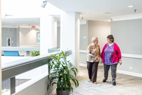 Two residents walking together in a bright hallway