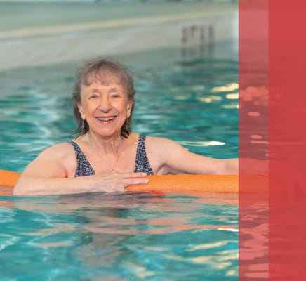 Senior resident swimming in pool with float