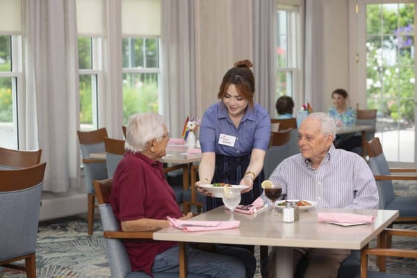 Staff serving food to residents in a dining area