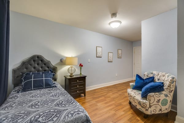 A cozy resident room with a bed and armchair