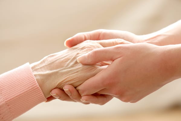 Hands of an elder and caregiver holding each other