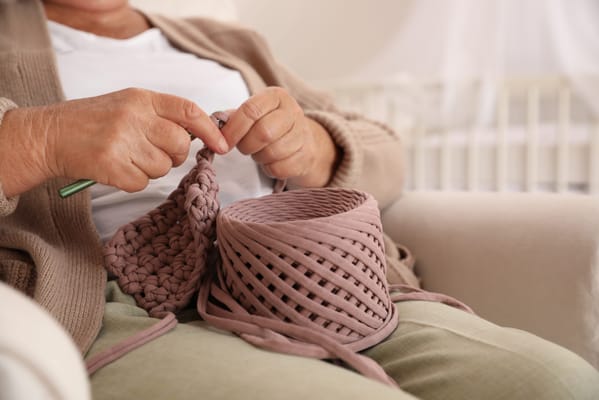 Senior resident crocheting in a cozy common area
