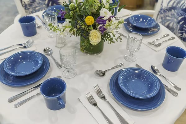 Dining table set with blue dinnerware and floral centerpiece