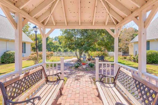 A gazebo with benches overlooking a landscaped garden