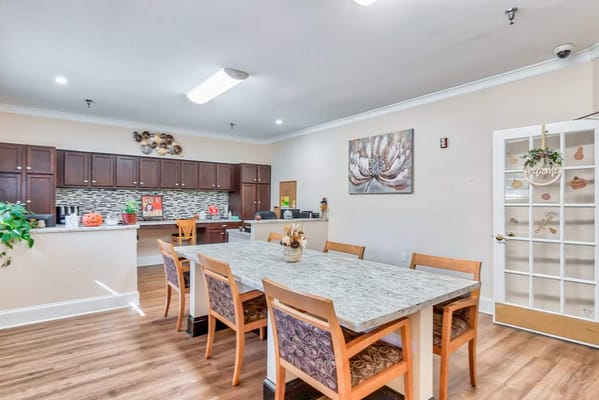 Bright dining area with a long table and kitchen access.