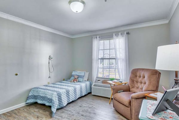 Cozy private resident room with a chair and bed