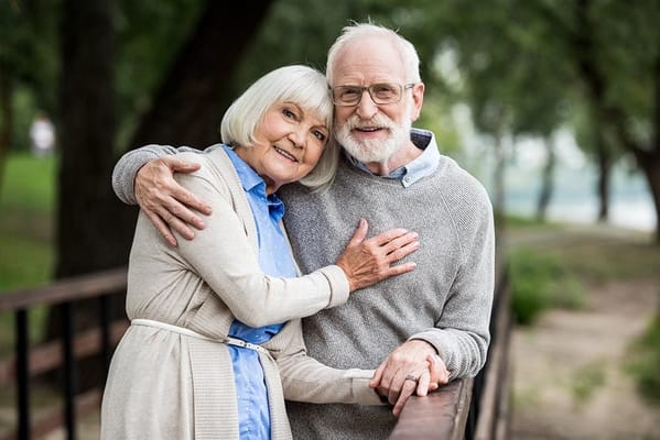 Senior couple smiling on a bridge in a park