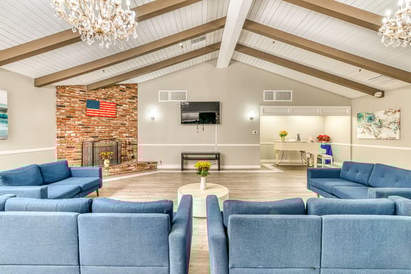 Bright common area with blue couches and fireplace