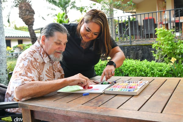 Staff assisting a resident with an activity outdoors