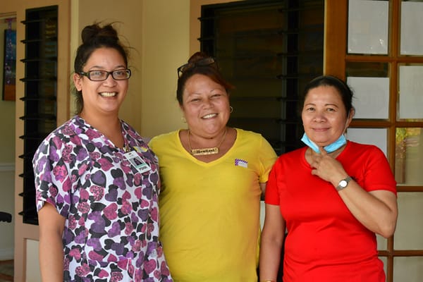 Three staff members smiling together indoors