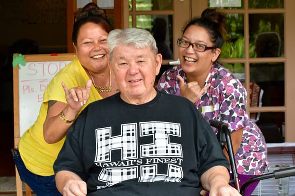 Residents and staff smiling together outside the facility