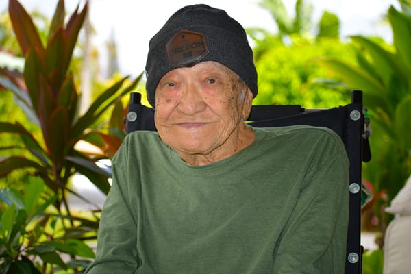Elderly man sitting outdoors among plants