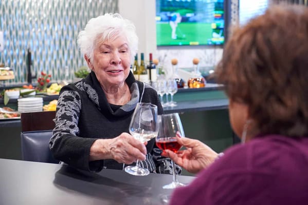 Two residents toasting with drinks in a dining area