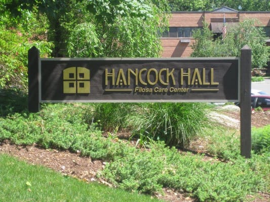Sign of Hancock Hall Filosa Care Center surrounded by greenery