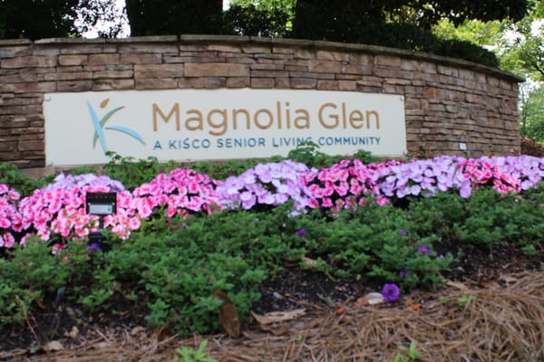 Exterior sign of Magnolia Glen with flowers