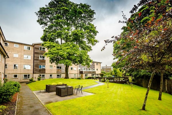Serene garden area of a retirement apartment with green grass and trees.