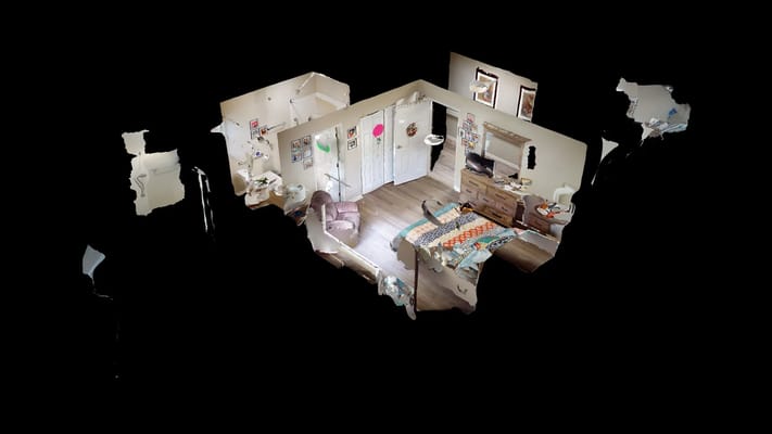 A spacious room in The Haven at Newnan, featuring a bed, chair, and decorative wall art.