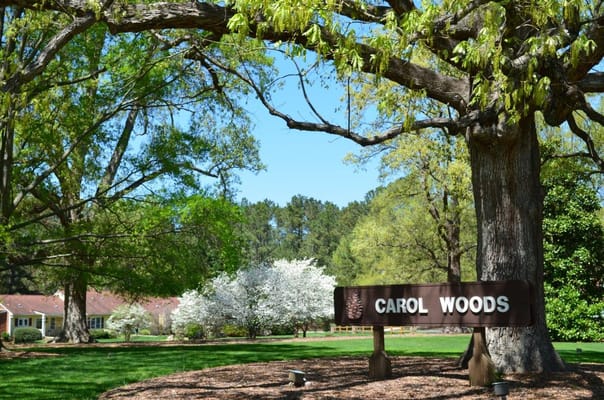 Sign for Carol Woods surrounded by greenery