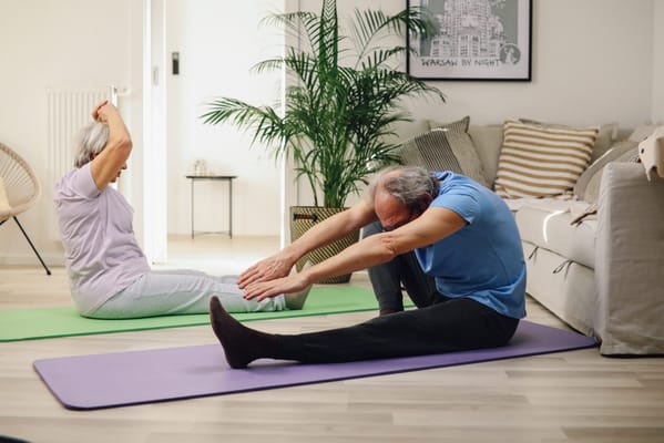 Two seniors practicing yoga in a bright indoor space