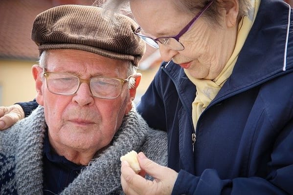 An elderly man and woman sharing a moment outdoors