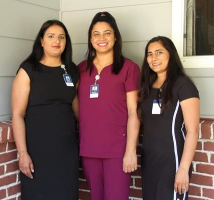 Three staff members posing outside the facility.
