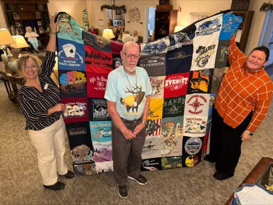 Residents displaying a colorful quilt in a common area