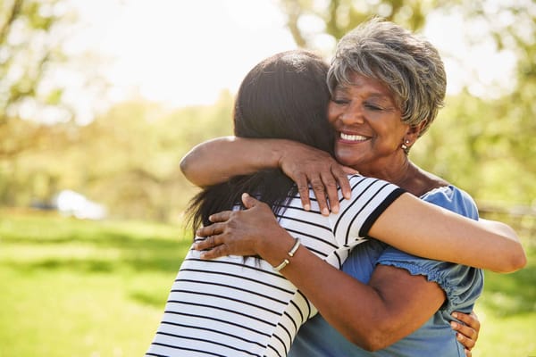 Two women embracing in a sunny outdoor space