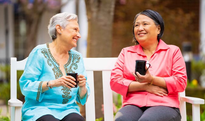 Two senior women enjoying coffee outdoors