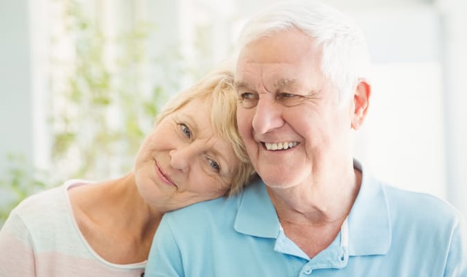 An elderly couple smiling together indoors