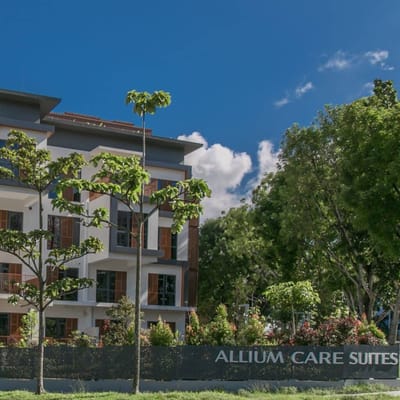 Exterior view of Allium Care Suites surrounded by greenery