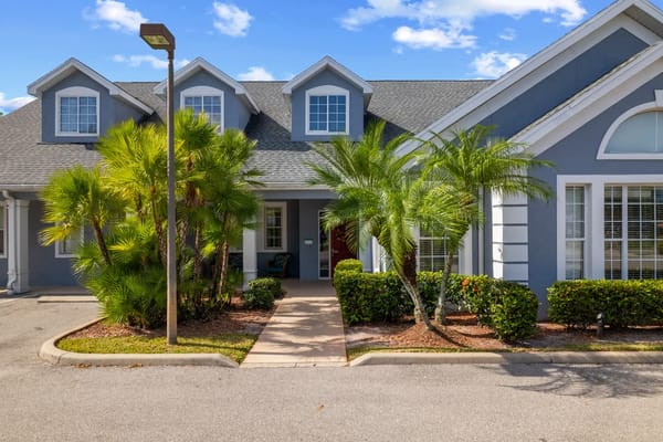Welcoming entrance with palm trees at Lehigh Acres senior living facility.