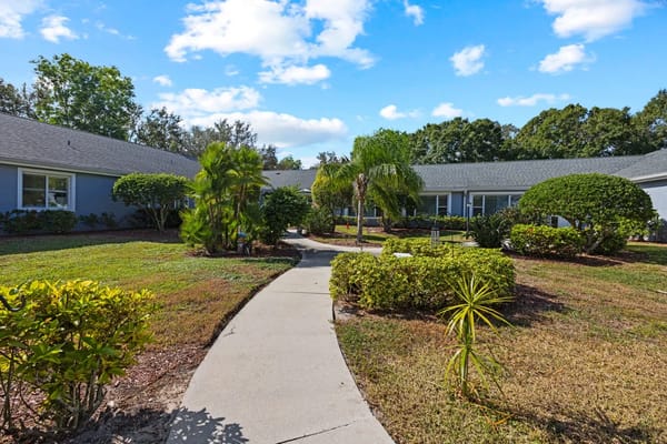 Pathway surrounded by greenery at Lehigh Acres senior living facility.