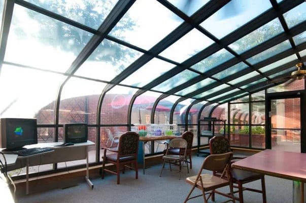 Sunroom in a senior living facility with chairs and desks.