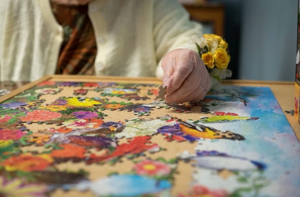 A senior resident working on a colorful puzzle