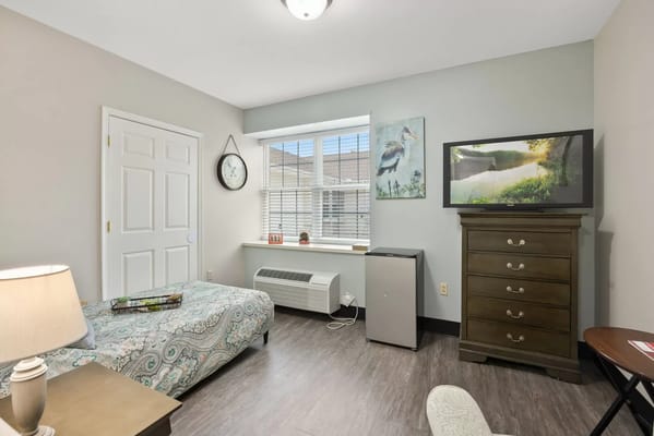 Interior view of a bedroom with a bed, dresser, and window