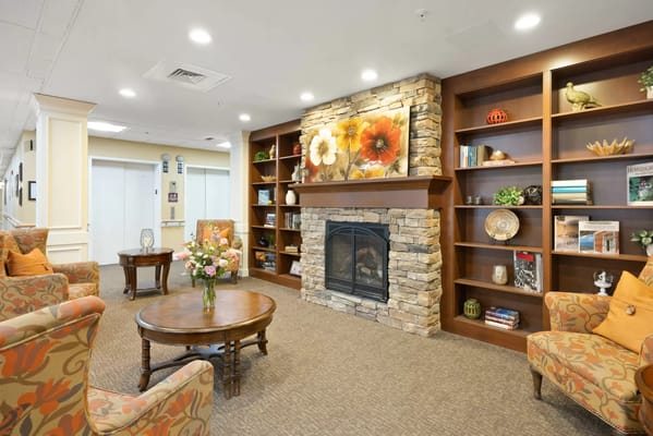 A cozy living room with a stone fireplace and floral decorations.