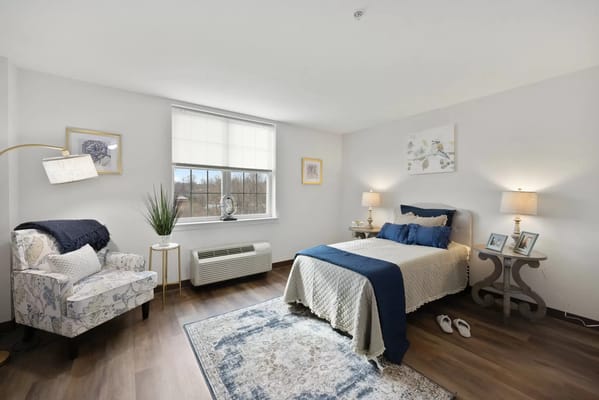 A neatly arranged bedroom with a bed, chair, and plants.