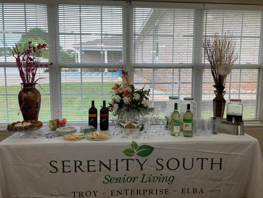 A refreshment table with drinks, snacks, and flowers at Serenity South Senior Living.