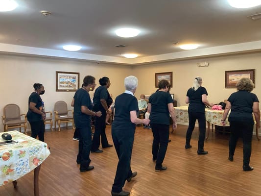 Group of residents engaged in a line dance activity in a senior living facility.