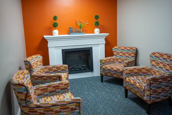 Cozy lounge area with colorful chairs and fireplace