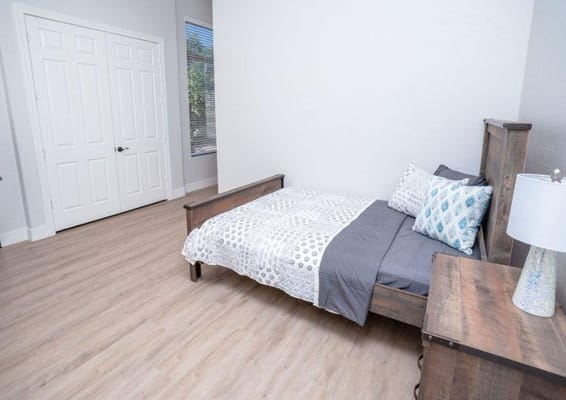 A well-furnished bedroom with a bed, nightstand, and closet.