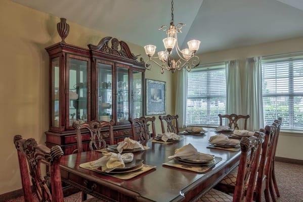 A beautifully set dining table with elegant chairs and a chandelier in a bright room.