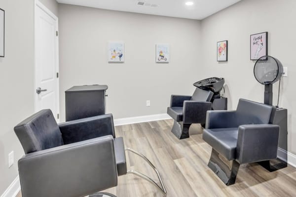 Interior view of the hair salon with black chairs and wall art.