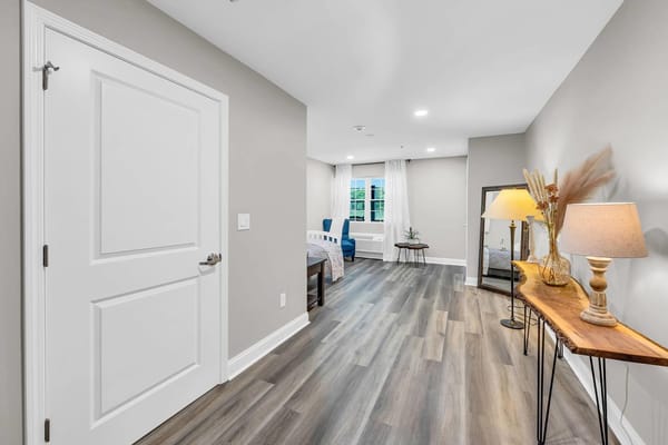A cozy bedroom interior featuring a bed, a small table, and decorative lamp.