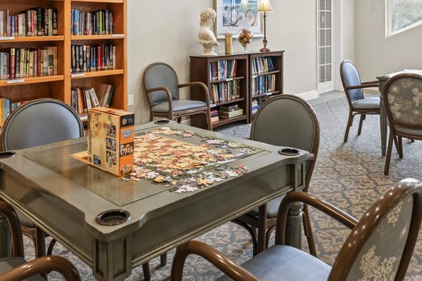 A view of a puzzle table in a reading area with bookshelves.