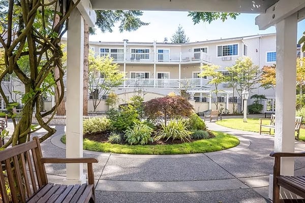 View of landscaped courtyard at Weatherly Inn Tacoma with benches and greenery.