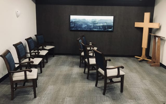 Interior of a prayer room with wooden chairs and a cross