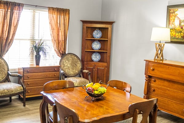 Living room with a wooden dining table, chairs, and decorative shelving.