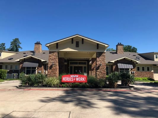 Exterior entrance of Heartis Conroe with 'Heroes at Work' banner